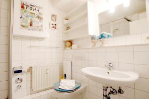 La salle de bains blanche est pourvue d'un lavabo et de toilettes. dans l'établissement Sandwall 2_ Whg_ 6, à Wyk auf Föhr