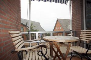 d'une table et de chaises en bois sur un balcon. dans l'établissement Sandwall 2_ Whg_ 6, à Wyk auf Föhr