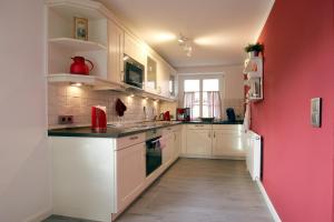 een keuken met witte kasten en een roze muur bij Luettmarsch 13_ Whg_ 1 in Wyk auf Föhr
