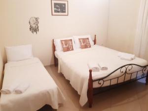 a bedroom with two beds with white sheets at Holly George Villa in Nea Plagia