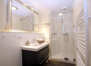 a white bathroom with a sink and a shower at Ohl Doerp 22 Pastoratshof_ Haus 3 in Wrixum