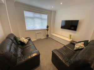 uma sala de estar com 2 sofás de couro e uma televisão de ecrã plano em Modern 2 bedroom apartment, with car parking. em Bitton