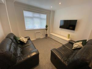 a living room with two leather couches and a flat screen tv at Modern 2 bedroom apartment, with car parking. in Oldland Common