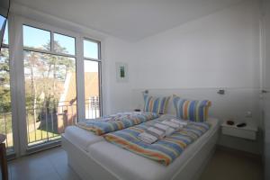 Cette chambre comprend un grand lit blanc et une fenêtre. dans l'établissement Stockmannsweg 14_ Whg_5 Haus am Me, à Wyk auf Föhr
