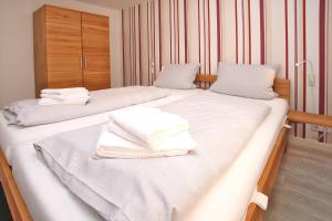 2 Betten in einem Zimmer mit weißen Handtüchern darauf in der Unterkunft Kiek Ut 9, Whg. 3 in Wyk auf Föhr