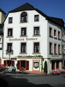 Un bâtiment blanc avec des personnes assises à l'extérieur dans l'établissement Gasthaus Huwer, à Bernkastel-Kues