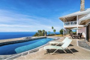 a house with a swimming pool next to the ocean at Luxe Designer Home, Best 180 Ocean View, Hot Tub & Pool estate in Papa Bay Estates