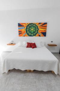 Un dormitorio con una cama blanca con un cuadro en la pared. en Hotel Lucero Chan, en Santa María del Oro