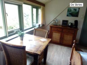 a dining room with a wooden table and some windows at B&B De Flecht - De Skries in Nijega