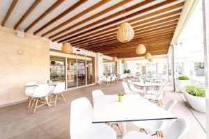 a restaurant with white tables and white chairs at Ibersol Siurell in Sa Coma