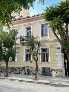 a yellow building with trees in front of it at Baloo Hostel in Athens