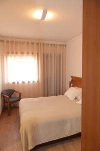 a bedroom with a white bed and a window at Casa Das Eiras in Macedo de Cavaleiros