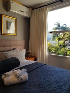a bedroom with a bed and a large window at Pousada Orquidea da Serra in Petrópolis