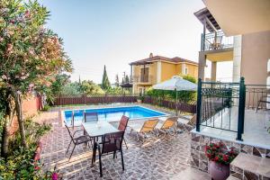 um pátio com uma mesa e cadeiras ao lado de uma piscina em Villa Nefeli em Trapezaki