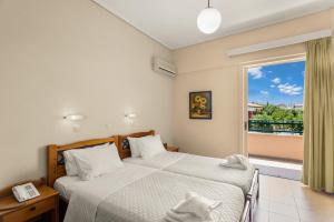 a bedroom with two beds and a large window at Lefktron Hotel in Stoupa