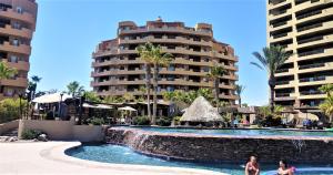 a pool at a resort with palm trees and a building at Bella Sirena 304-A - Elegant Oceanview Condo on Sandy Beach in Puerto Peñasco
