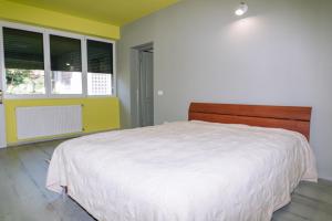 a bedroom with a white bed and two windows at The Home in Timişoara