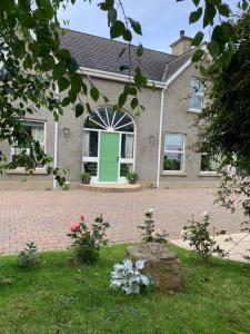 una casa con una puerta verde en un patio de ladrillo en Windyridge en Aghagallon