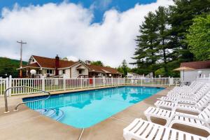 a swimming pool with white chairs and a fence at Riverbank's Pemi Cottage in Lincoln