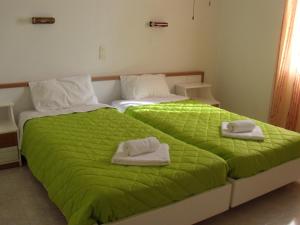 a bedroom with two beds with green sheets and towels at Antigoni Apartments in Acharavi