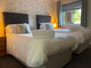 a bedroom with two beds with white sheets and a window at Village Limits Bed and Breakfast Rooms in Woodhall Spa