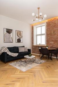 a living room with a black couch and a brick wall at Keskväljaku apartment - with sauna and AC in Võru