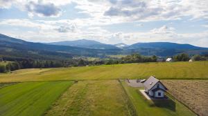 a small house in a field with mountains in the background at Domek POD GOLCOWEM in Limanowa