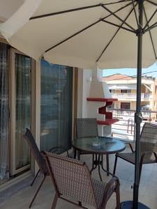 eine Terrasse mit einem Tisch, Stühlen und einem Sonnenschirm in der Unterkunft Holiday's Nea Peramos Kavala's in Néa Péramos