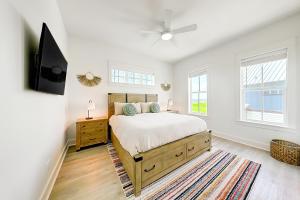 a bedroom with a bed and a tv and windows at The Spanish Dagger in Port Aransas