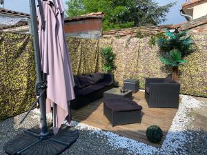 un patio con sofá y sombrilla en Cocooning Bed&Spa, en Toulouse