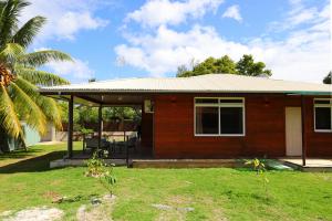 una piccola casa in mattoni con portico e palma di Fare Omoe a Fare (Huahine Nui)