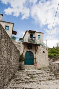 a stone house with a green door and stairs at Napoleon Zaglis Guesthouse in Kalarrites
