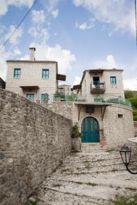 a stone house with a stone wall and a green door at Napoleon Zaglis Guesthouse in Kalarrites