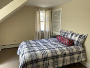 a bedroom with a bed with a plaid blanket and a window at Mt Holly SKI & LAKE HOUSE 4 and 2 bedroom house, 2 separate homes, 2 bathrooms each, 8 mins to Okemo Mountain in Mount Holly