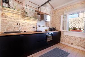 a kitchen with black cabinets and a sink and a window at Art Loft Venetian Well in Corfu Town