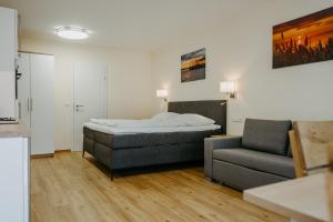 ein Schlafzimmer mit einem Bett, einem Sofa und einem Stuhl in der Unterkunft Chill & Relax Apartments in Neusiedl am See in Neusiedl am See
