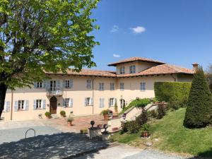 a large tan building with a tree in front of it at Agriturismo La Casa in Collina in Canelli