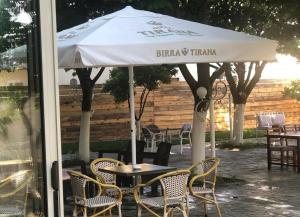 uma mesa e cadeiras sob um guarda-sol branco em Hotel Xhelili em Cërrik