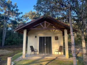 a small house with chairs in front of it at Pousada Chalés da Lua in Munhoz