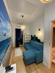 a living room with a blue couch and a painting at Blue Wave Garden in Dziwnówek