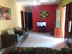 a living room with a couch and a tv at chácara ouro verde in Beberibe