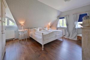 a bedroom with a large white bed and two windows at Landhaus Vilmnitz - Wohnung 8 in Vilmnitz