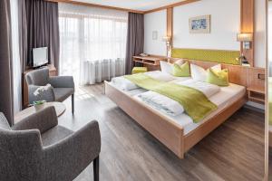 a hotel room with a large bed and two chairs at Hotel AlpenSonne Ruhpolding Chiemgau Karte in Ruhpolding