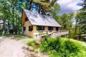een klein geel huis met een metalen dak in het bos bij 230 Ghia Farm Road in Ludlow