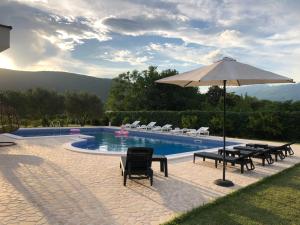 - Piscina con mesas, sillas y sombrilla en Villa Paraiso, en Mostar