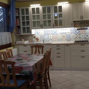 MÁRIA apartman في بالاتونكريستور: مطبخ مع طاولة وكراسي ومطبخ مع دواليب بيضاء