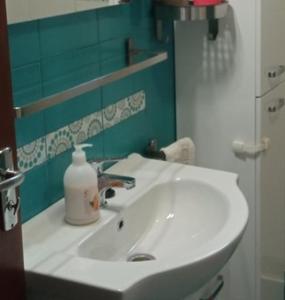 un lavabo blanco con una botella de jabón. en MÁRIA apartman en Balatonkeresztúr