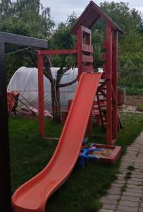 un parque infantil con un tobogán rojo en el césped en MÁRIA apartman en Balatonkeresztúr