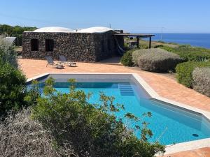 a swimming pool in front of a house at Dammusi I Jardina in Pantelleria