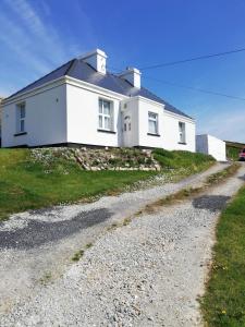 a white house on a hill with a gravel road at Glenhill - Newly renovated in a unique location in Belmullet